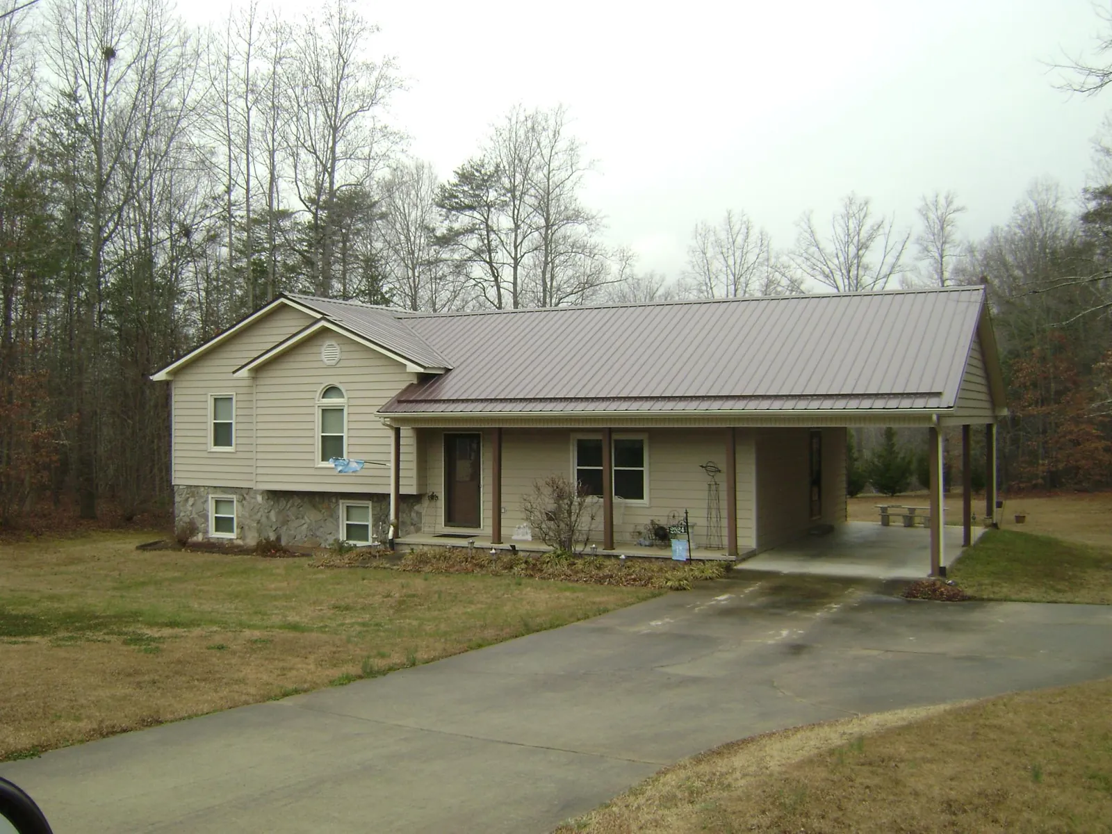Brown metal roof on a tan split level home with an attached carport in Norwood